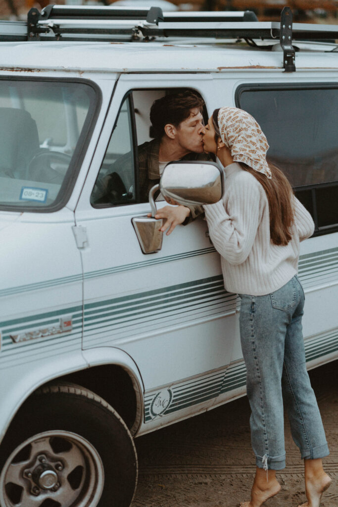 Couple kissing in front of their camper van.
